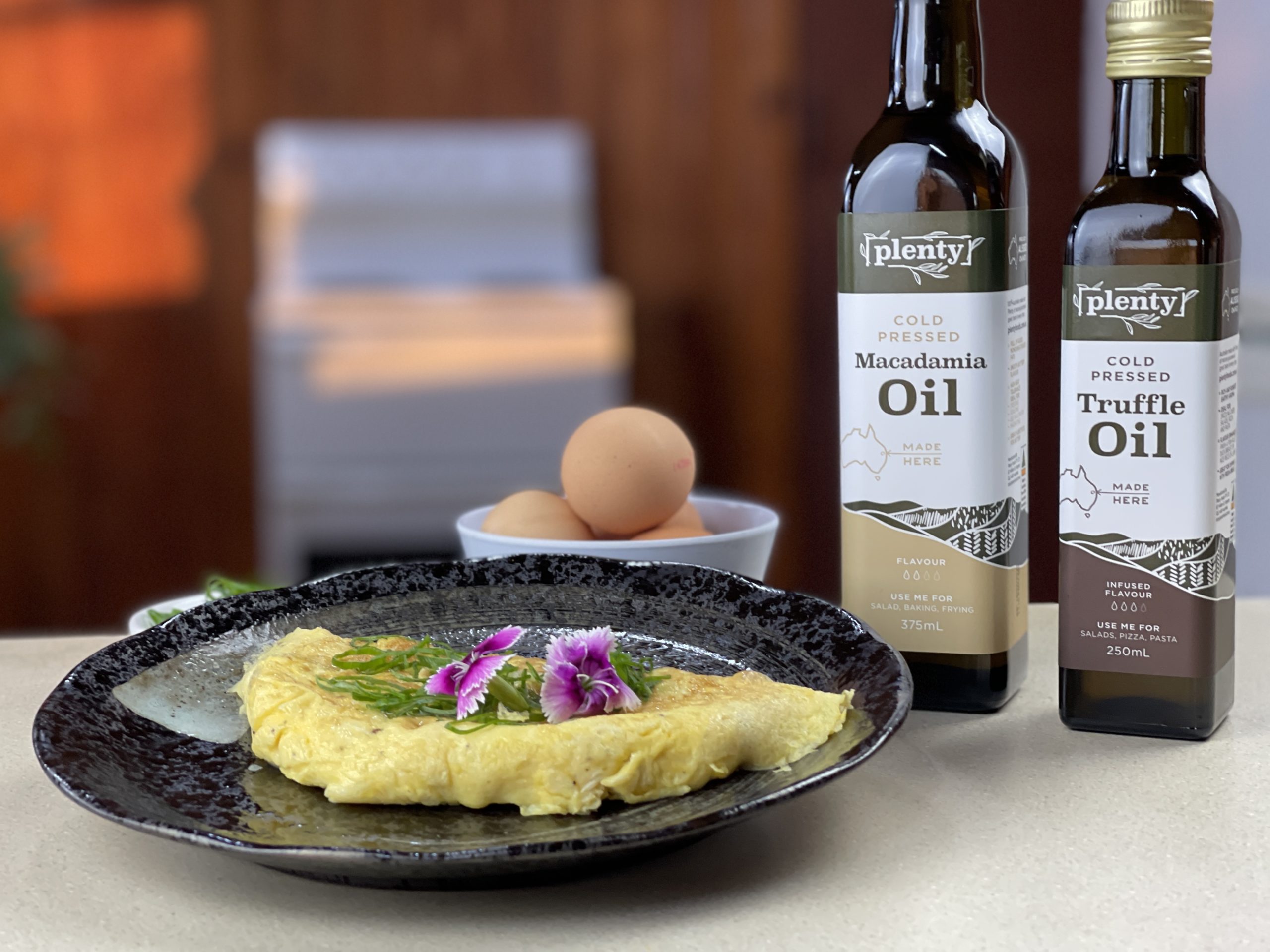 Bottles of Plenty Macadamia Oil and Plenty Truffle Oil. A plate with omelette and truffle and macadamia oil.